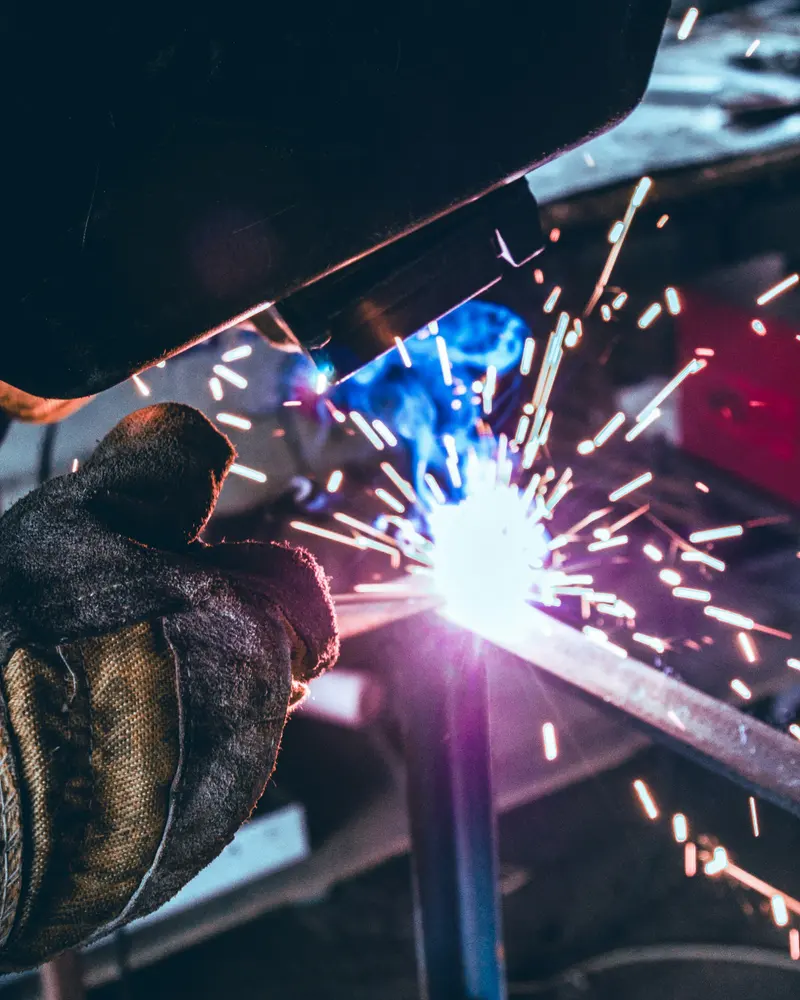 Soldador trabalhando em uma peça de metal na oficina